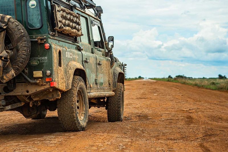 Land Rover Defender vert sur une piste de terre rouge